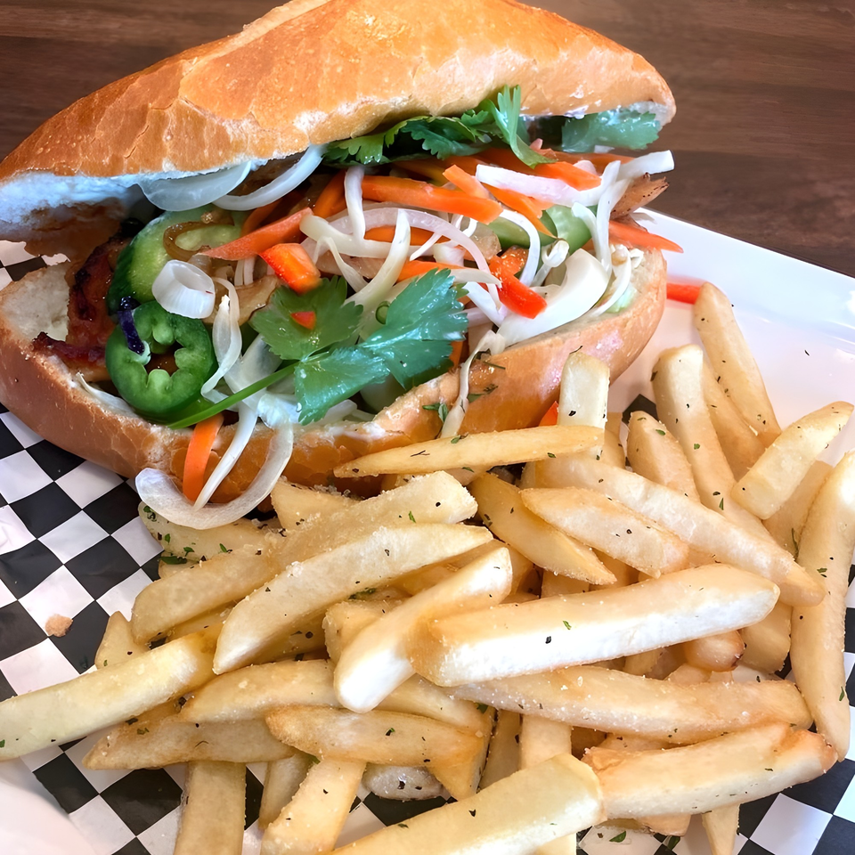 MoDak Korean Chicken's banh mi sandwich with jalapeños, cilantro, and pickled vegetables, served with fries.