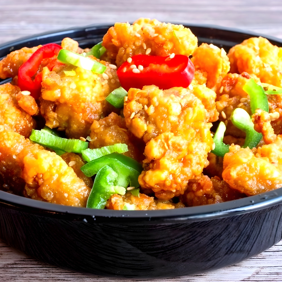 MoDak Korean Chicken's fried chicken pieces, garnished with red and green peppers and sesame seeds.